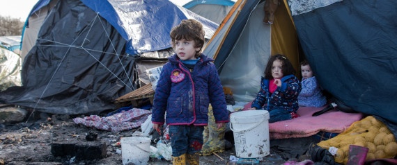 Children of Kurdish migrants gather outside a tent at the Grande Synthe migrant camp near Dunkerque in northern France on December 23, 2015. More than 2,000 migrants, mostly Iraqis and Kurds, live in the camp. The UN refugee agency and the International Organization for Migration (IOM) said this week more than one million migrants and refugees reached Europe this year, most of them by sea, more than four times the figure for 2014. / AFP / DENIS CHARLET