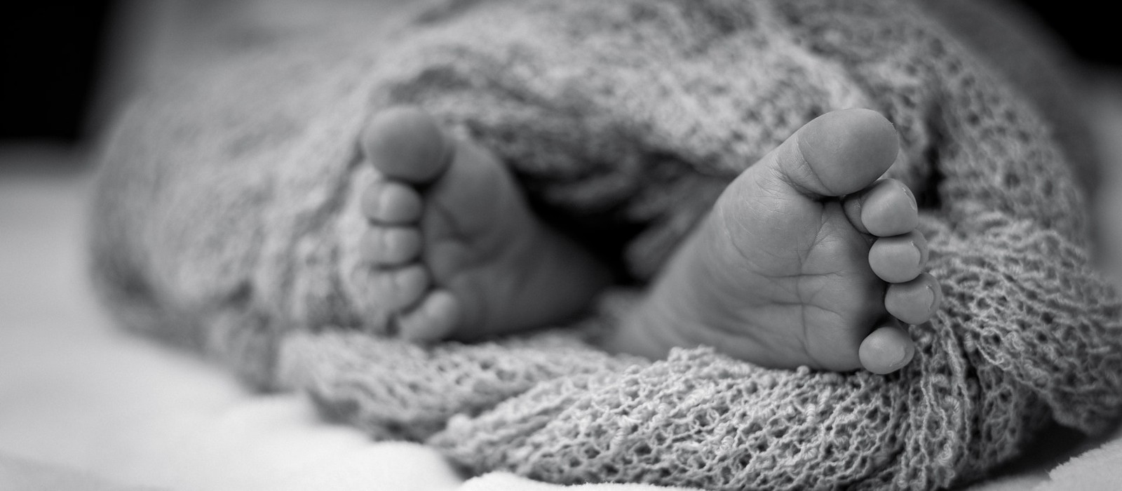 des pieds d'enfant depassent d'un linge. photo en noir et blanc